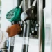 Mão retira bico verde de combustível em bomba de posto