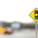 Placa amarela com desenho de semáforo em destaque à frente de trânsito desfocado