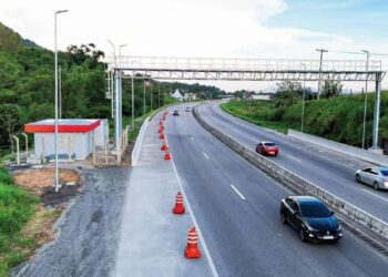 Carros trafegam por rodovia monitorada por pórtico eletrônico de pedágio