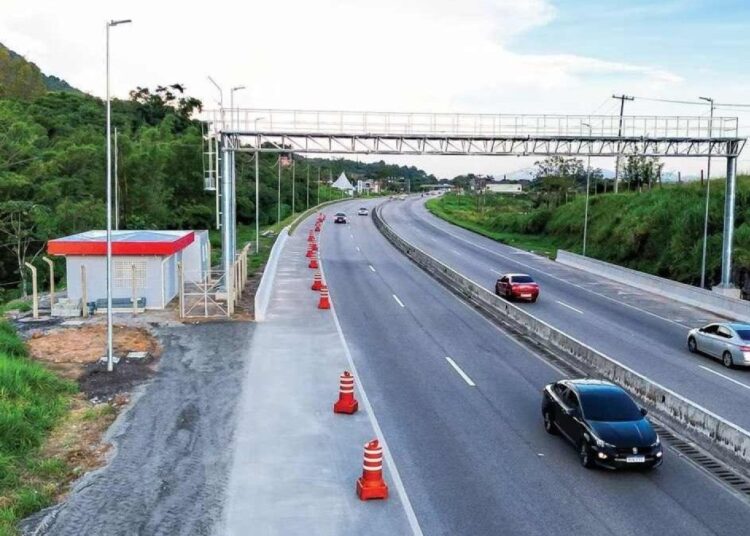 Carros trafegam por rodovia monitorada por pórtico eletrônico de pedágio