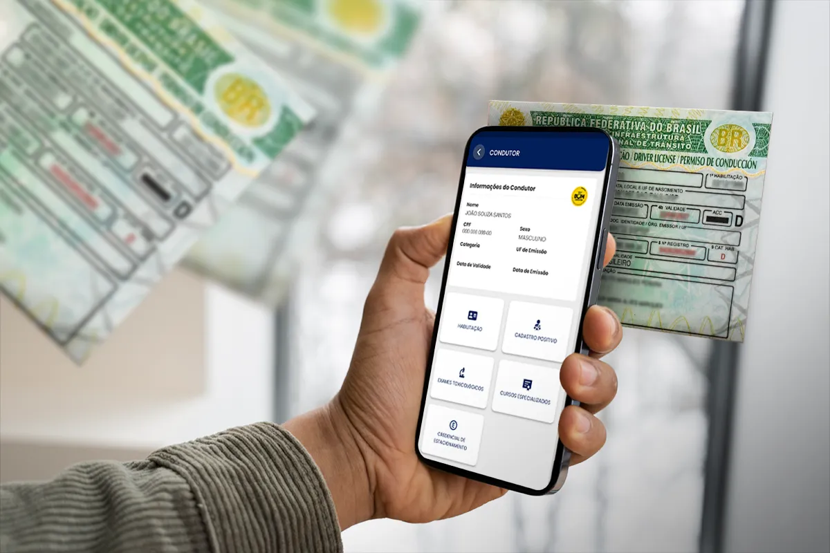 Mão segurando smartphone com tela do aplicativo CNH do Brasil exibindo dados de condutor, com CNH física desfocada ao fundo