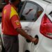 Frentista com camisa vermelha e amarela da Shell abastece Ford Fiesta branco em posto de combustíveis