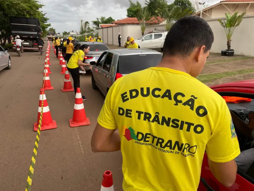 Agentes com camisetas amarelas do Detran-RO abordam condutores em blitz educativa com cones sinalizando a via