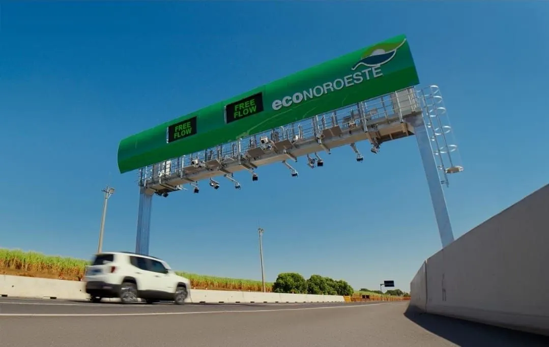Carro branco trafega em rodovia sob pórtico verde com letreiro Free Flow Econoroeste