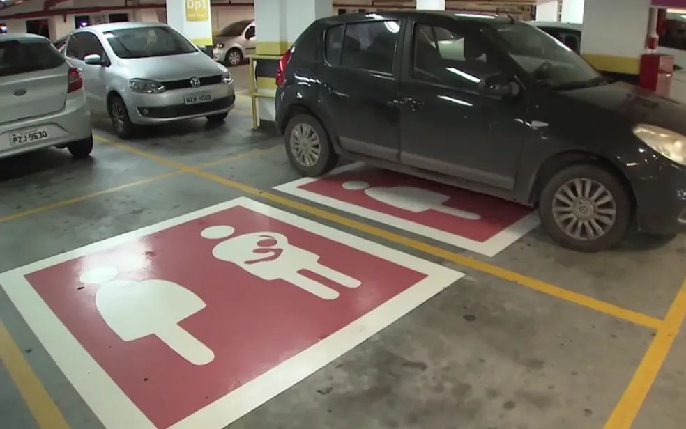 Estacionamento de shopping com vagas preferenciais sinalizadas com pictograma rosa de gestante e mãe com bebê no colo