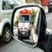 Ambulância branca do SAMU 192 com sirene ligada refletida no espelho retrovisor de um veículo
