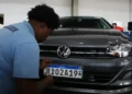 Funcionário uniformizado fixando placa padrão Mercosul RK02A19 em Volkswagen Virtus cinza