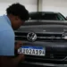 Funcionário uniformizado fixando placa padrão Mercosul RK02A19 em Volkswagen Virtus cinza