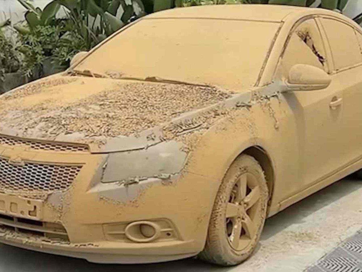 Chevrolet Cruze sedã completamente coberto por lama bege, com placa, faróis e vidros obstruídos pela sujeira