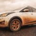 Hyundai HB20X branco estacionado totalmente coberto por barro vermelho após passagem por estrada de terra