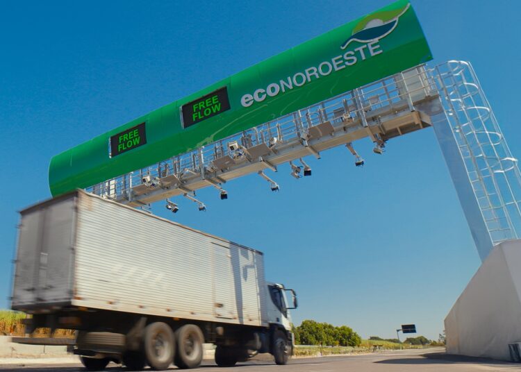 Caminhão branco passa sob pórtico verde free flow da EcoNoroeste com câmeras e sensores em rodovia de São Paulo