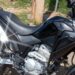 Honda XRE 300 preta estacionada em ambiente externo com bagageiro lateral metálico e motor monocilíndrico prateado