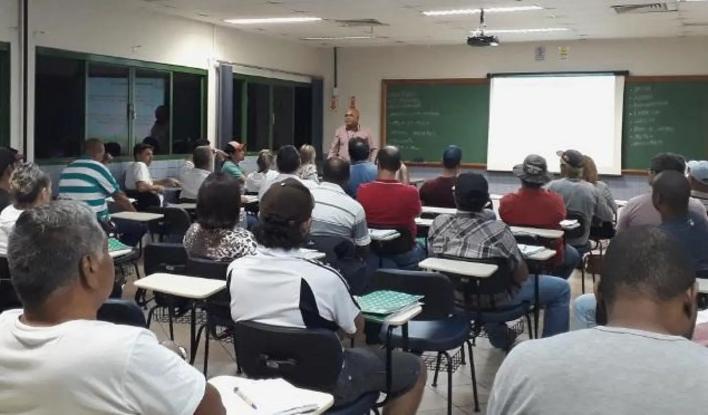 Condutores sentados em carteiras escolares durante aula de reciclagem exigida para motoristas com CNH suspensa