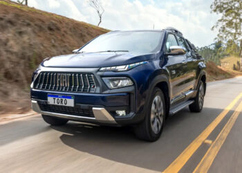 Picape Fiat Toro 2026 azul escura com grade frontal vertical inspirada na Maserati e luzes LED pontilhadas em estrada rural