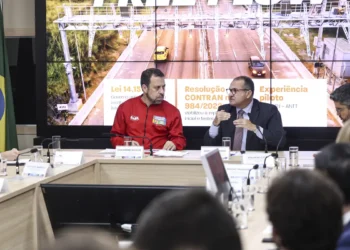 Guilherme Boulos de jaqueta vermelha e George Santoro de terno escuro em coletiva sobre pedágios eletrônicos