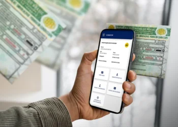 Mão segura smartphone exibindo app CNH do Brasil com dados de condutor e CNH física ao fundo.