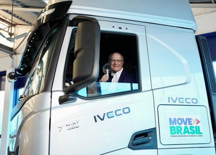 Geraldo Alckmin sorrindo faz sinal positivo na cabine de caminhão branco IVECO S-Way com logo Move Brasil
