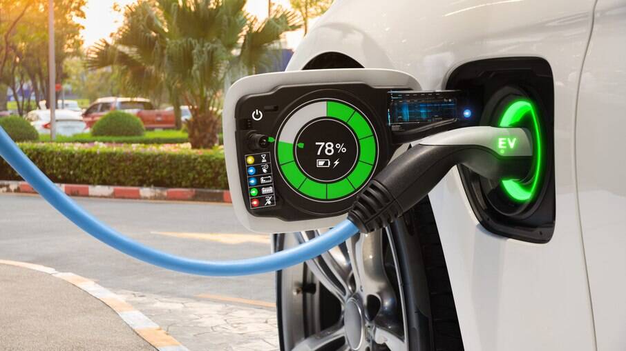 Veículo elétrico branco conectado ao carregador, display mostra 78% de carga com indicador verde e símbolo EV iluminado