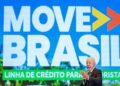 Presidente Lula de terno escuro aplaude em evento do Move Brasil com painel azul ao fundo exibindo logo e texto do programa.