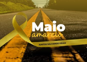 Laço amarelo sobre rodovia asfaltada com faixas contínuas e texto 'Maio Amarelo: Juntos Salvamos Vidas'.