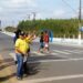Agentes de trânsito orientam pedestres e motoristas em faixa de segurança com placa "Respeito ao Pedestre"