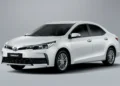 Toyota Corolla sedã branco em estúdio com fundo neutro, vista dianteira-lateral mostrando faróis LED e rodas de liga