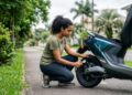 Mulher verificando a pressão do pneu de moto elétrica preta em área residencial