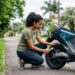 Mulher verificando a pressão do pneu de moto elétrica preta em área residencial