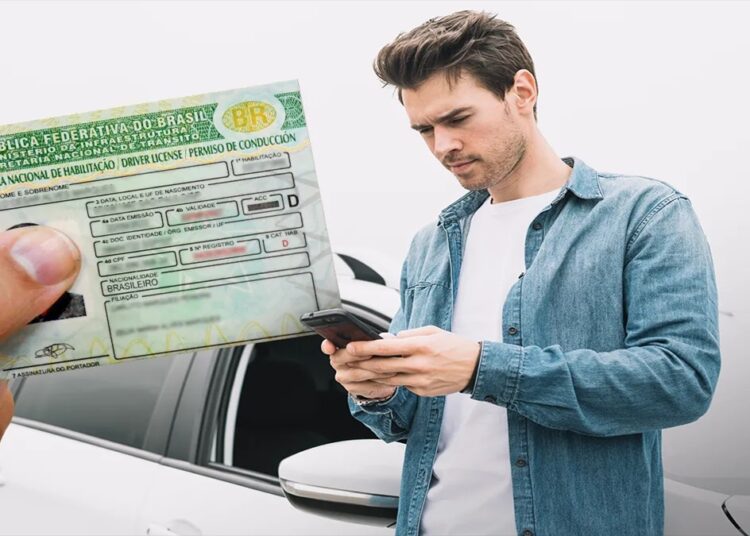 Homem jovem usa celular ao lado de carro branco enquanto mão segura carteira de motorista brasileira