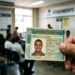 Mão segura CNH brasileira em sala de atendimento ao cidadão, pessoas sentadas aguardam