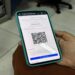Pessoa segurando celular mostrando site falso da CNH Social com QR Code e valor R$ 62,41
