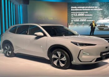 SUV Geely EX5 branco em destaque durante lançamento com painel digital ao fundo