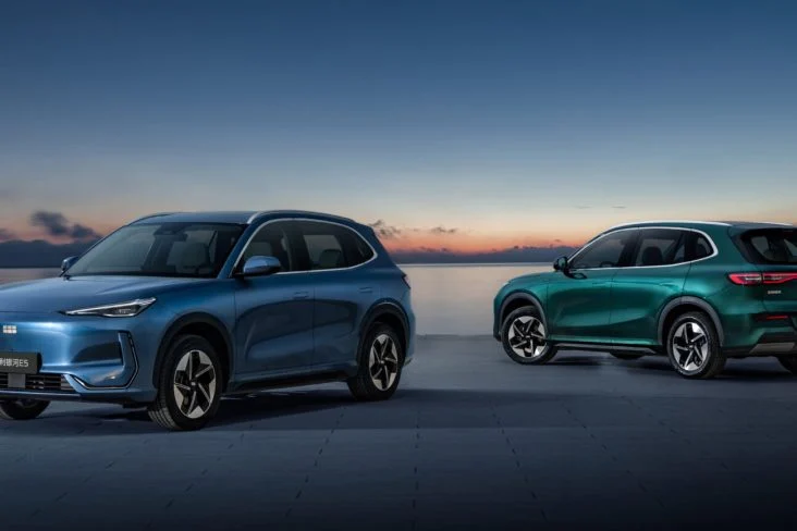 Dois SUVs Geely EX5 2026, azul e verde, lado a lado ao entardecer, vista externa
