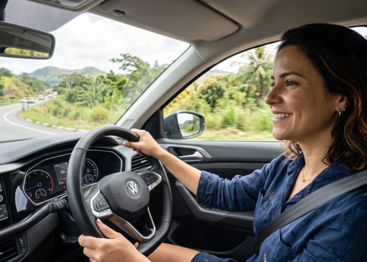 Mulher jovem dirigindo carro Volkswagen em estrada com vegetação e montanhas ao fundo