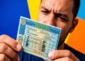 Homem segura CNH brasileira mostrando categorias A, B, C, D e E com ícones de veículos permitidos