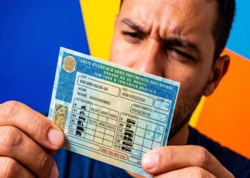 Homem segura CNH brasileira mostrando categorias A, B, C, D e E com ícones de veículos permitidos