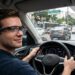 Homem dirige carro usando óculos inteligentes com navegação projetada no trânsito de São Paulo
