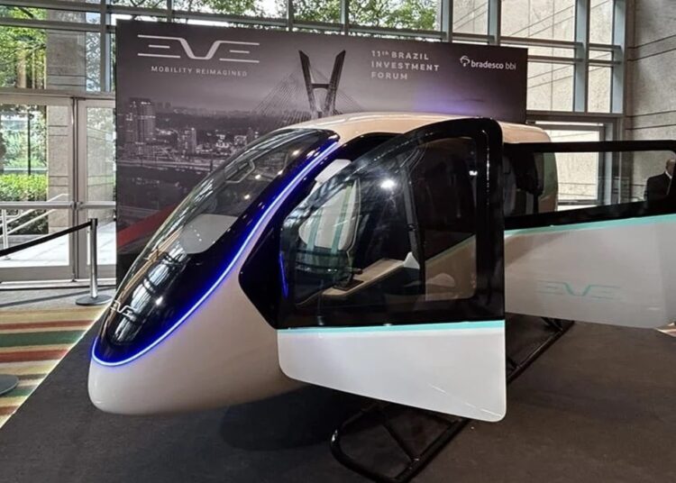 Cabine futurista do eVTOL Eve em exposição com iluminação azul neon, bancos internos e painel ao fundo do Brazil Investment Forum