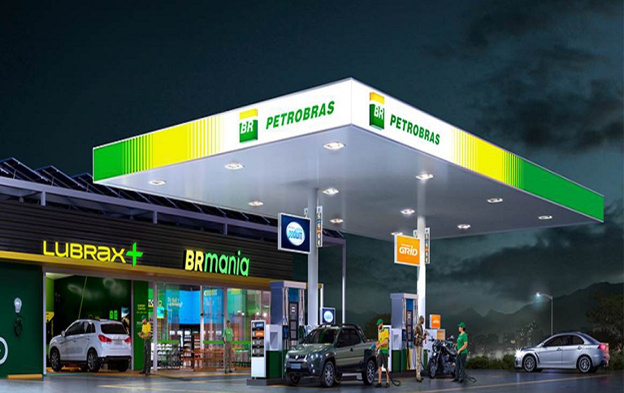 Funcionários abastecem carros em posto Petrobras com letreiros BRmania e Lubrax durante a noite
