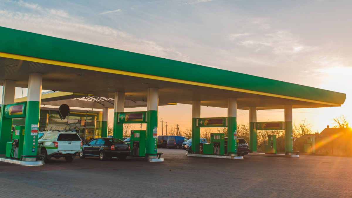 Posto de combustível moderno com carros abastecendo ao pôr do sol.