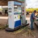 Frentista abastece Volkswagen Gol prata com etanol em posto BR Petrobras, canas-de-açúcar ao redor da bomba