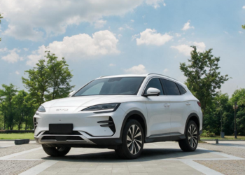 SUV branco BYD Song Plus estacionado ao ar livre, céu azul, árvores ao fundo.