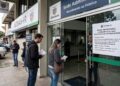 Cidadãos aguardam na porta do Detran-PR, que suspendeu temporariamente os agendamentos para exames de CNH.
