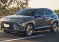 Hyundai Kona Hybrid cinza escuro trafegando em estrada com árvores ao fundo e placa Novo Kona Hybrid