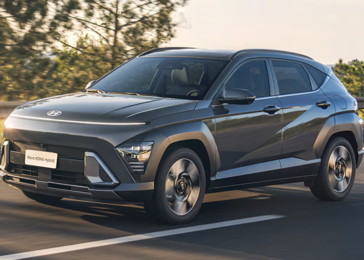 Hyundai Kona Hybrid cinza escuro trafegando em estrada com árvores ao fundo e placa Novo Kona Hybrid