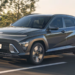 Hyundai Kona Hybrid cinza escuro trafegando em estrada com árvores ao fundo e placa Novo Kona Hybrid