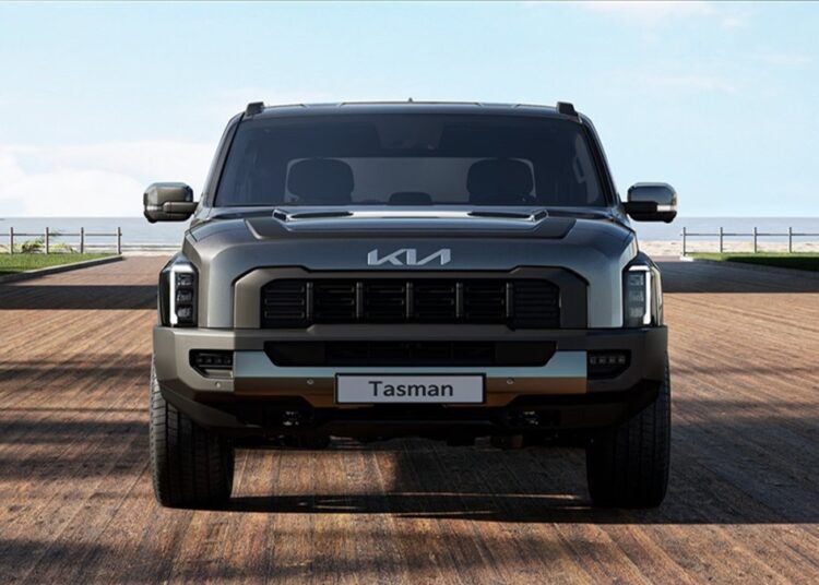 Visão frontal da picape Kia Tasman cinza com grade preta robusta e logo da Kia sobre estrutura moderna