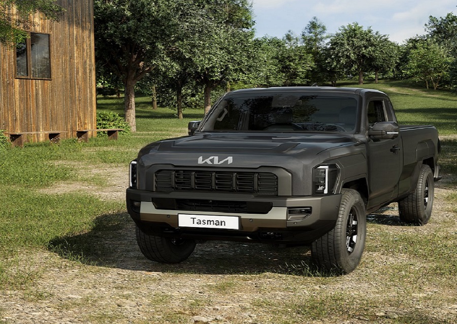 Kia Tasman cinza escuro estacionada em área rural, com grade frontal robusta e logotipo Kia no capô