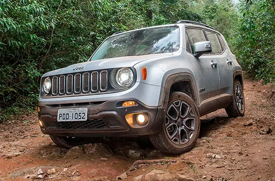 Jeep Renegade prata com placas PDD-1052 em estrada de terra, rodeado por vegetação densa