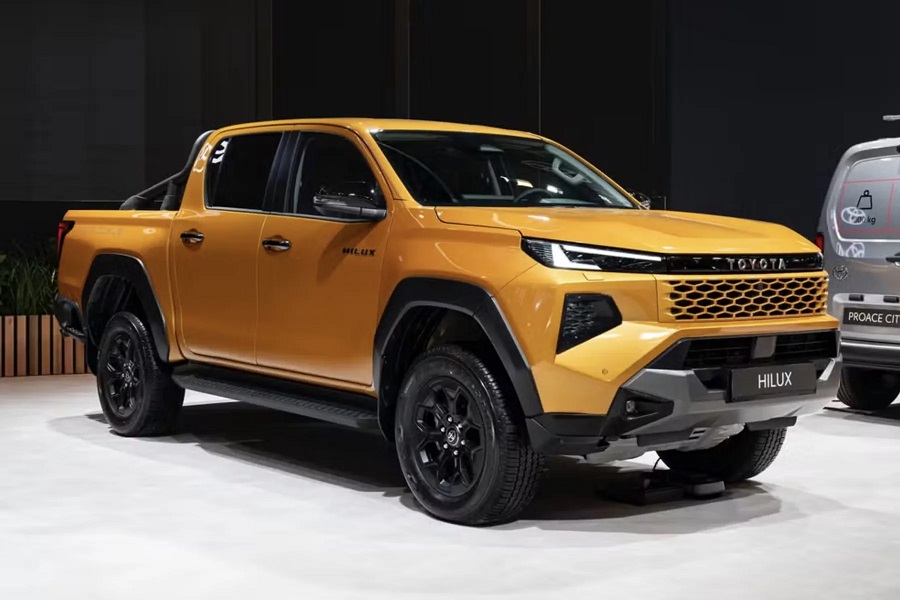 Toyota Hilux 2027 dourada em exposição, grade frontal preta e rodas escuras destacadas